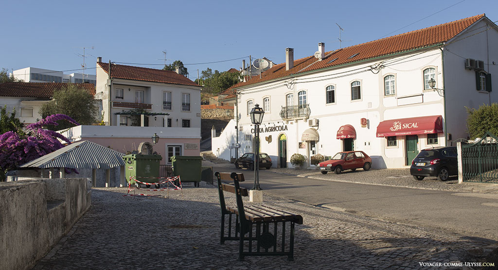 grande rue d'Abiul, avec à gauche les poubelles et de l'autre coté de la rue la banque et le bar
